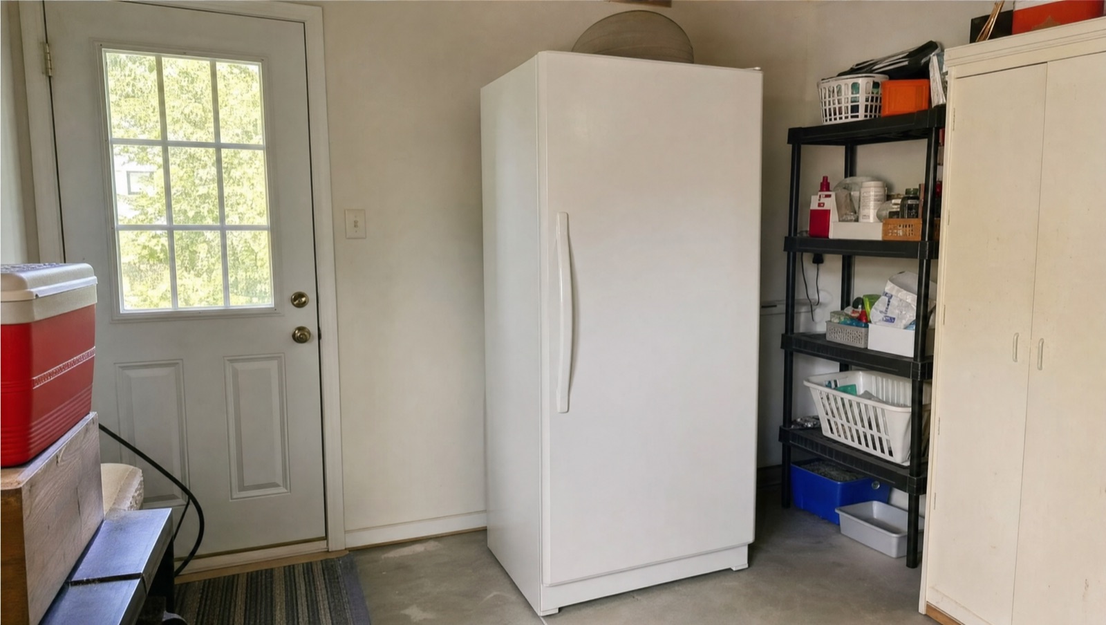 White upright freezer in the garage of a Baltimore, MD home, where winter cold and summer heat cut into a freezer's cooling capacity, a setup Doctor Maintenance diagnoses often