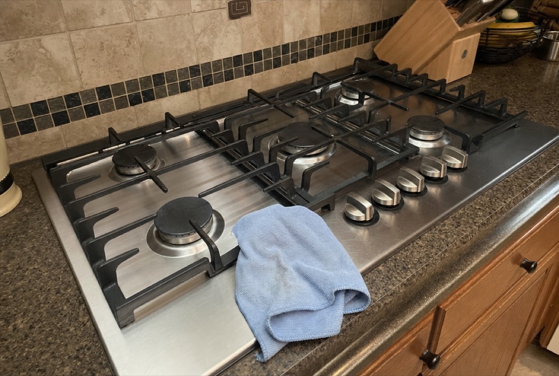 A stainless cooktop being checked and cleaned during a Baltimore, MD repair by Doctor Maintenance