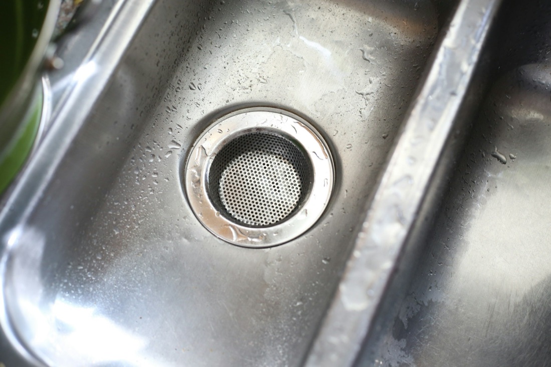 A kitchen sink drain and strainer in a lived-in Baltimore, MD kitchen serviced by Doctor Maintenance