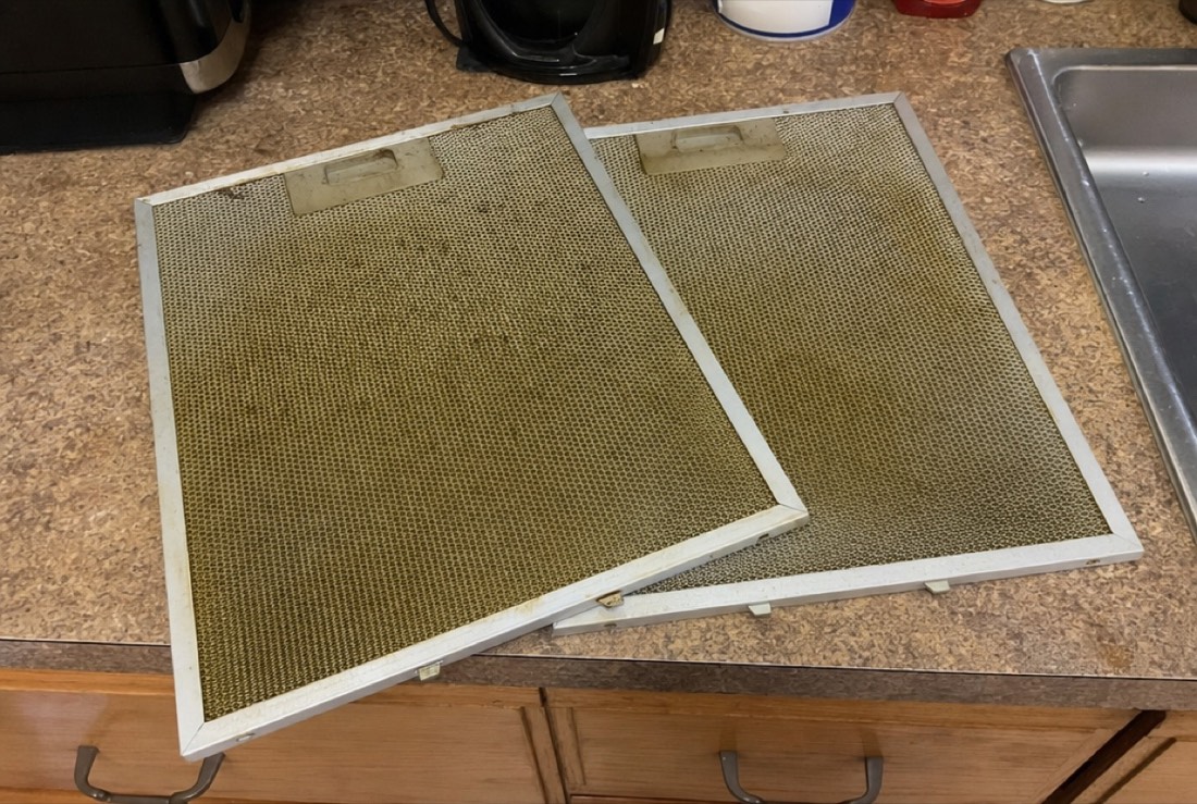 Greasy range hood filters removed for cleaning during a Baltimore, MD repair by Doctor Maintenance